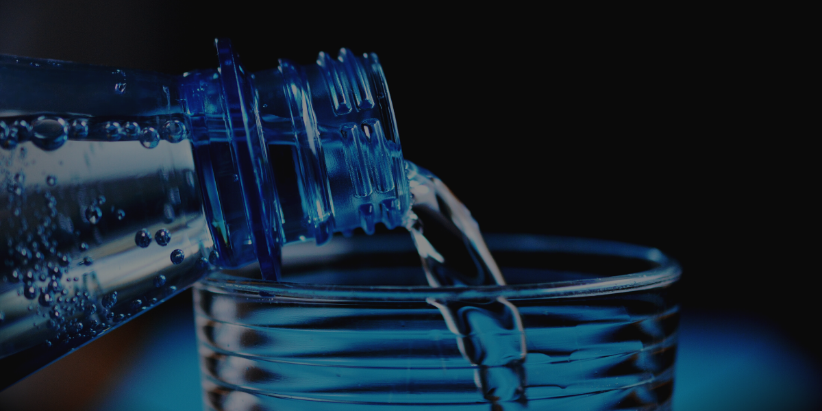 a bottle of water being poured into a clear glass